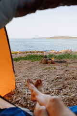 Fototapeta na wymiar view from a tent on the shore of a lake or sea, camping in nature, wild life in a tent. freedom and relaxation from the hustle and bustle of the city, travel blogger and mental health on vacation