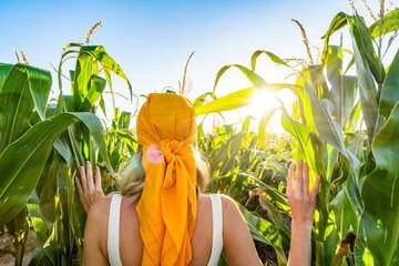Woman walking through organic green corn fields. Nature lover. Summer vibes. Healthy food.