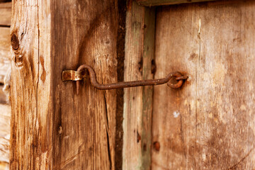 Vintage rusty metal hook or bolts on a wooden antique door.
