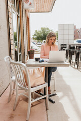 Young female professional works outside coffee shop on laptop computer
