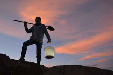 Man carrying shovel & bucket of light