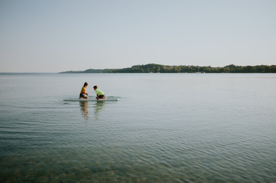 Two brothers sitting on a paddle board on a serene lake