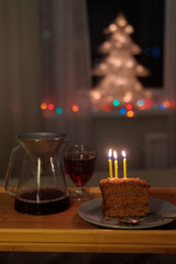 christmas decorations at home, lights garlands on the Christmas tree for new year and Christmas. cake and candles for a birthday or Christmas Eve celebration. soft selective focus. celebration and