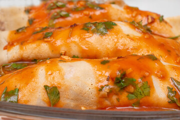chicken pancakes topped with tomato sauce filled with basil leaves in glass bowl