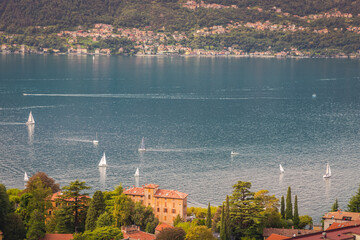 Village and sailboats on Lake Como near Bellagio at sunset, Italy