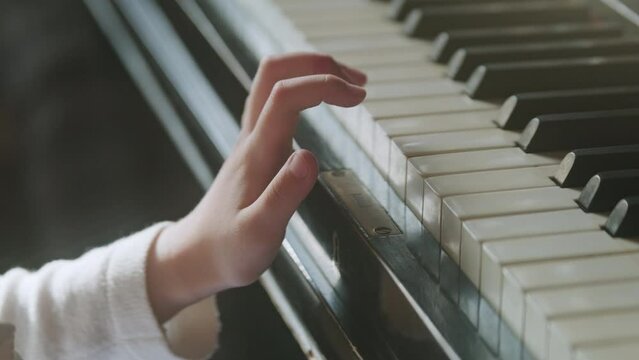 Crop child playing piano during lesson