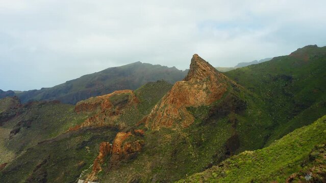 Picturesque landscape. Blue sky. Ridges of rocks rise above the green cactus vegetation in spring. Mountain Risco Blanco. Go everywhere. Tenerife, Canaries, Spain. Top of cliffs in mist, foggy weather
