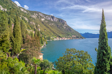 Fototapeta premium Idyllic Lake Como coastline with village and cypresses at sunny day, Italy