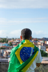 man with brazil flag on his back looking at the city