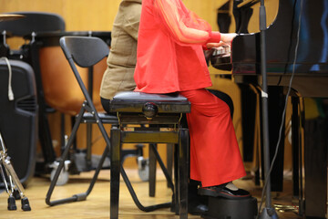 Fototapeta na wymiar A little girl in a red suit plays the piano while studying at a school lesson with a teacher in the classroom.The concept of musical education for children