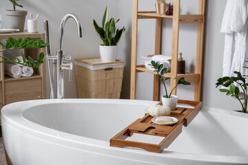 Wooden board with soap, loofah and houseplant in bathroom