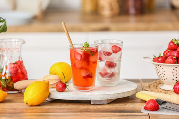 Tray with glass of cold strawberry lemonade on table in kitchen