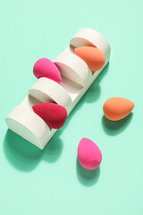 Stand with makeup sponges on green background