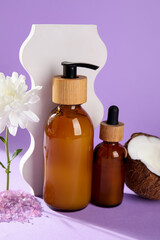 Bottles of natural cosmetic products on lilac background