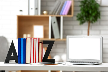 Stylish holder with books and laptop on table in room