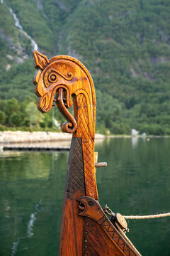 Dragon head at the front of a viking boat on the water