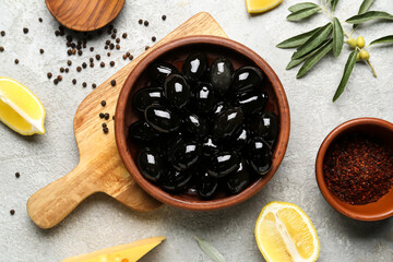 Composition with plate of tasty black olives, spices and lemon on light background