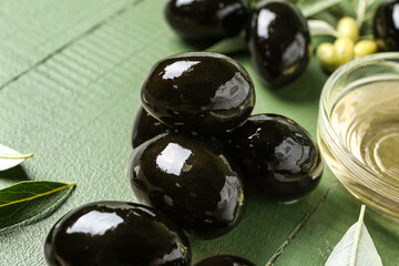 Tasty black olives on color wooden background, closeup
