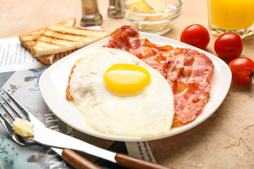 Plate with tasty fried egg and bacon on table