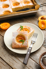 Plate with pieces of tasty apricot pie on wooden table