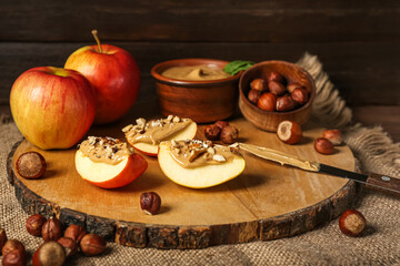 Board of tasty apple wedges with nut butter on wooden table, closeup