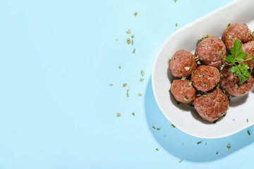 Plate with tasty meat balls and herbs on blue background