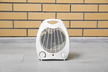 Electric fan heater near brick wall