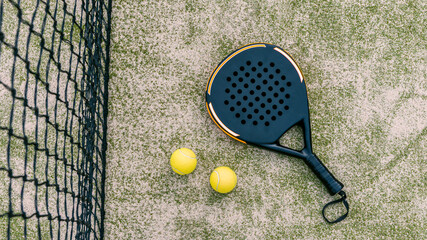 Top view of yellow balls on floor near of padel tennis racket in green court