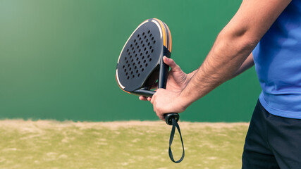 Professional monitor of padel holding black racket on green court. Game concept