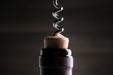 Opening wine bottle with corkscrew on dark background, closeup - obrazy, fototapety, plakaty