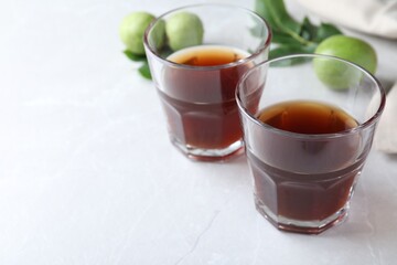 Delicious liqueur and fresh walnuts on light table, closeup. Space for text