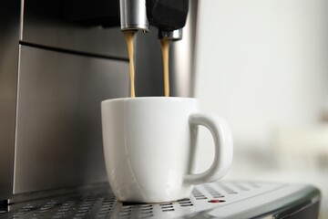 Espresso machine pouring coffee into cup against light background, closeup