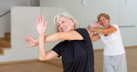 Portrait of an elderly dancing woman practicing vigorous swing at a group training session in the studio of dance