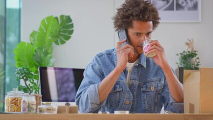 Man running online business making boutique candles at home talking on mobile phone - shot in slow motion