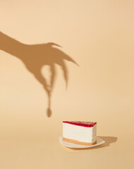 Halloween minimal concept with cheesecake and witch or zombie hand shadow. Creative spooky holiday fun background.