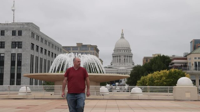 Caucasian male in maroon shirt walking to camera on the Monona Terrace in Madison, Wisconsin in slow motion.