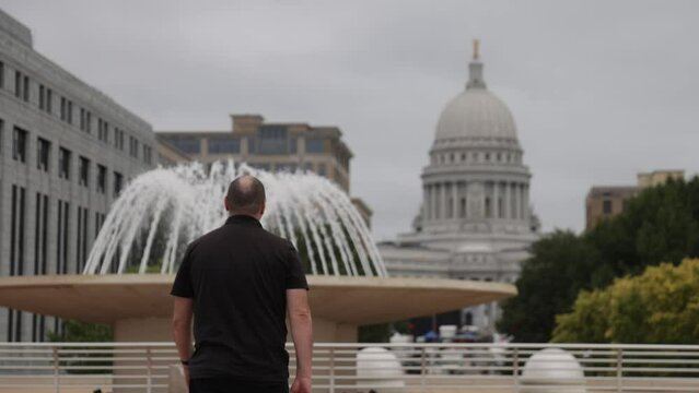 Caucasian male in black clothes walking away from camera on Monona Terrace in Madison, Wisconsin.