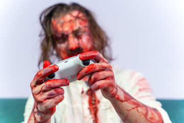 Man in form of bloody zombie obsessed with gambling addiction. Person in corpse makeup holds joystick in hands. Gambling addiction, development of aggression cruelty in children tendency to violence
