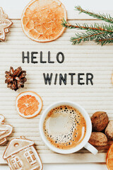 Lettering hello winter on letter board. Fir branches, dried oranges, nuts and a cup of coffee. minimalistic new year background 2023