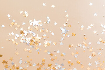 golden confetti stars on beige background top view