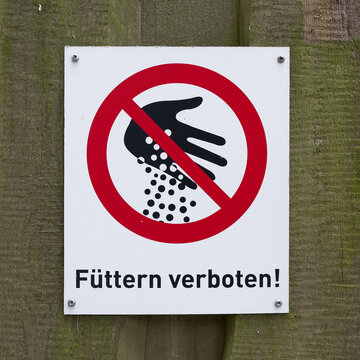 Schild mit der Aufschrift F&uuml;ttern verboten am Zaun in einem Tierpark in Deutschland