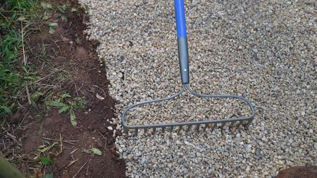 Slow Motion Raking Pea Gravel Stone On Top Of Landscape Fabric For A Garden Home Improvement Project.