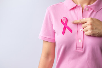 Pink October Breast Cancer Awareness month, woman hand hold pink Ribbon and wear shirt for support people life and illness. National cancer survivors month, Mother and World cancer day concept - obrazy, fototapety, plakaty
