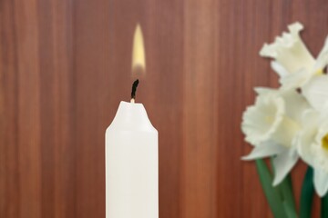 Flame candle with flower. A white wax candle with flowers burns in honor of the memory.
