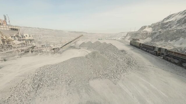 FPV drone view of A big yellow Wheel loader in a quarry is loading wagons with rubble
