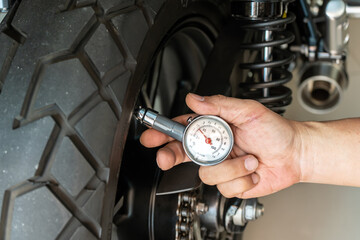 Man holding pressure gauge for checking  motocycle tyre pressure ,maintenance,repair motorcycle...