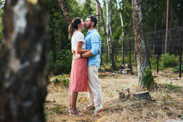 Portrait of a young couple kissing on a date in the woods. Front view.