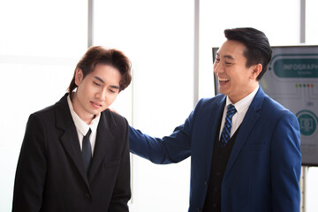 Cheerful senior manager or team leader encouraging an employee by touching at his shoulder and...