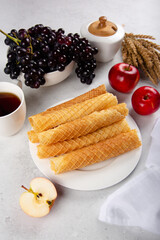 Homemade waffles on a white plate with apples and grapes.