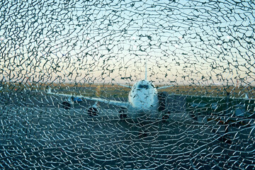 Aircraft silhouette view over the cracked window in the airport. Catastrophe and crash concept
